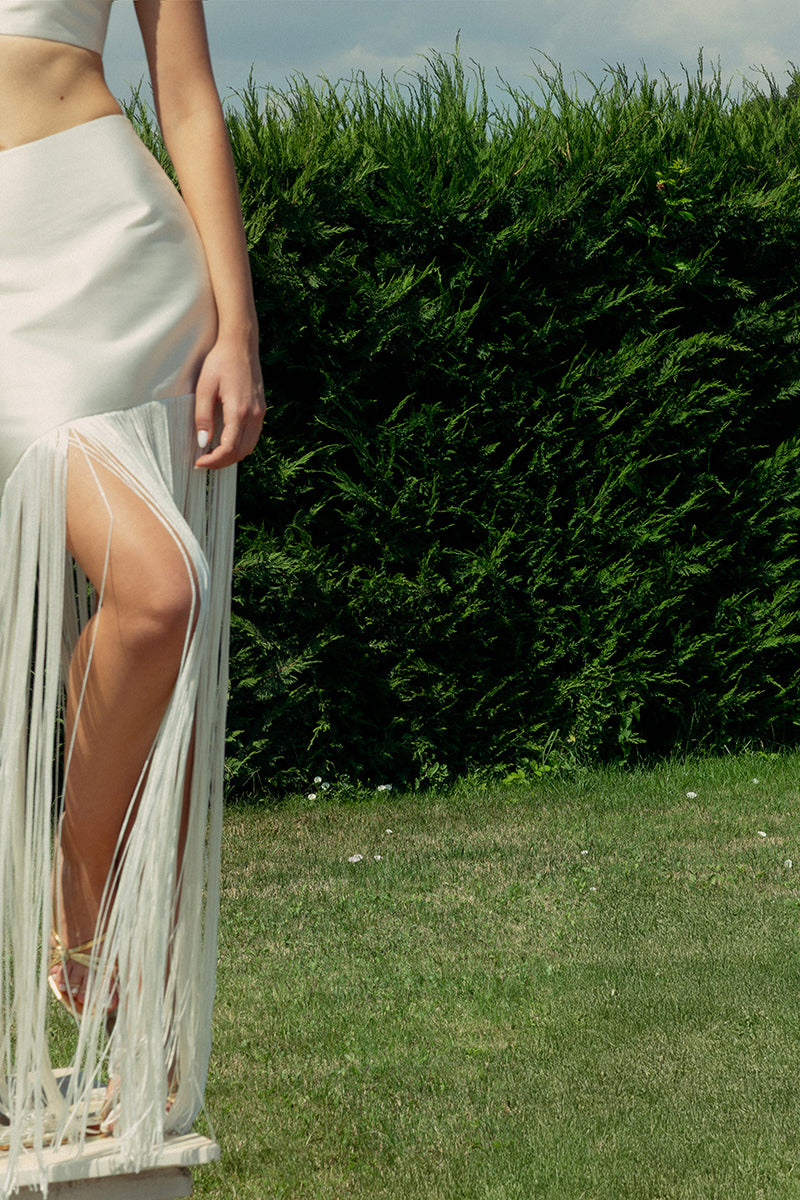 Ivory fringe maxi skirt by Monika Dimova, flowing fabric with fringe details, styled for a boho-chic look.