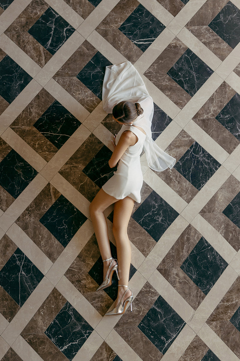 White embellished cape mini dress by Monika Dimova, featuring intricate detailing and stylish design for elegant occasions.