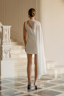 White embellished cape mini dress by Monika Dimova, featuring intricate details and elegant design for stylish occasions.