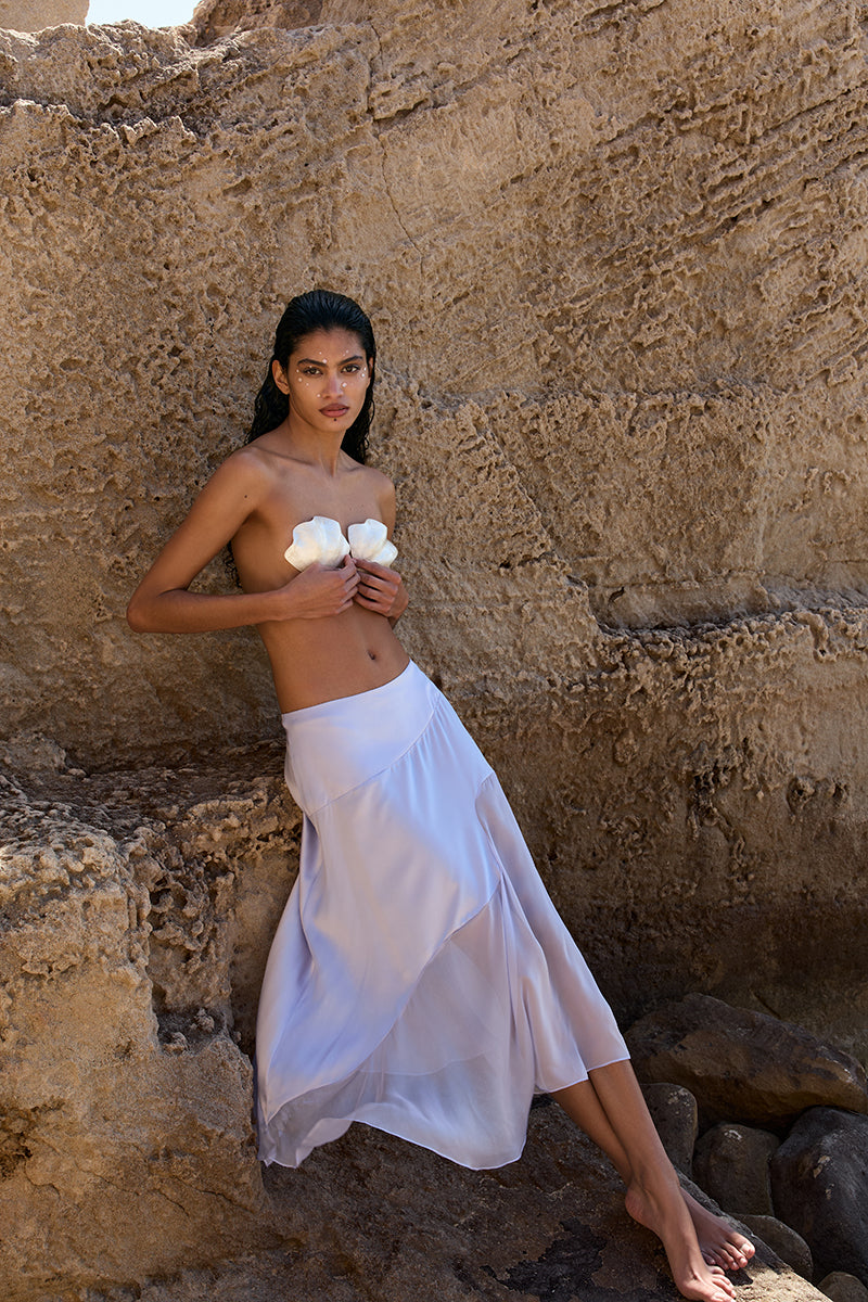 IKINITA Nausica lilac midi skirt with flowy fabric and high waist, shown on a model in a stylish, casual setting.