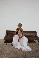 White IKINITA Innocent maxi skirt with flowing fabric and a relaxed fit, displayed on a hanger in this product image.