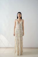 Beige deep V-neck tiered pleated maxi dress from DOC BAN, flowing fabric with layered pleats, full-length dress on model.