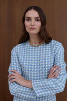 Undress Carmela sky blue tweed mini dress displayed on a hanger, showcasing its textured fabric and stylish short design.