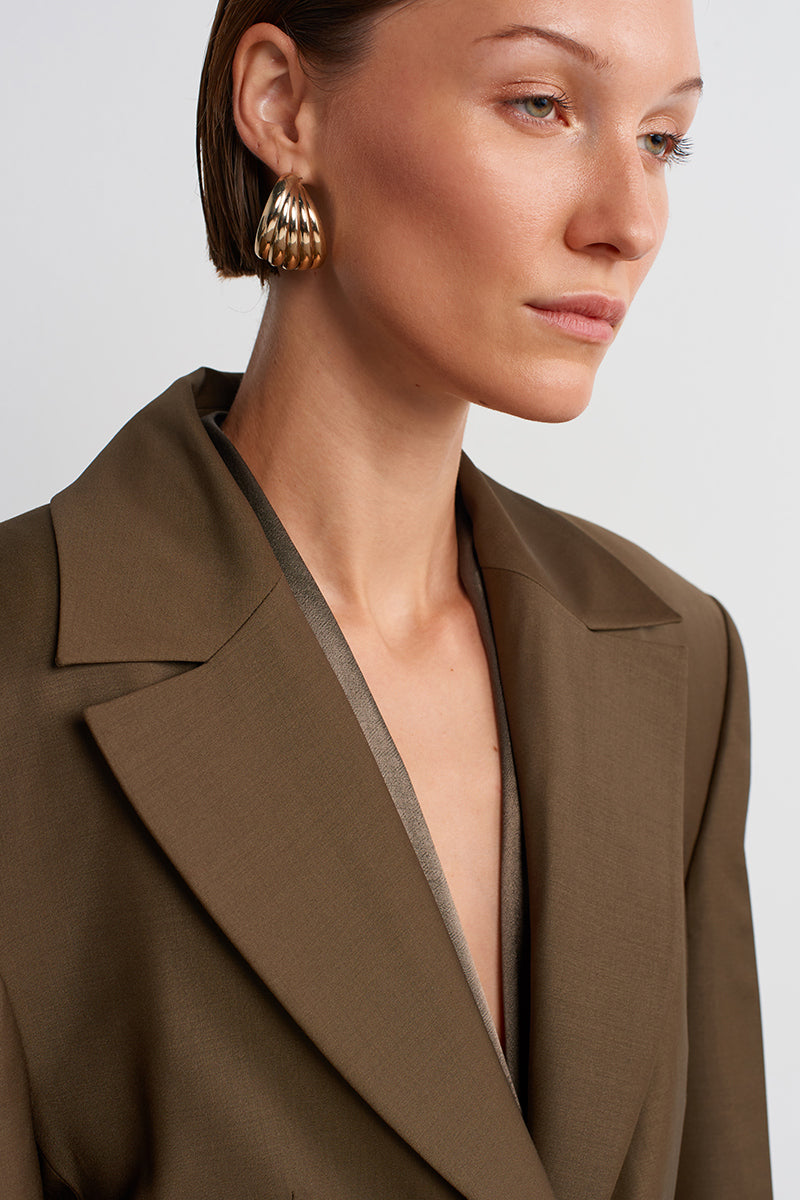 Acaria Studio Earth Blazer in Hazelnut Brown, tailored blazer with lapels and front pockets, displayed on a hanger.