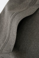 Brown long wool cape coat by JINSUN draped over a hanger, showcasing its textured fabric and elegant length.