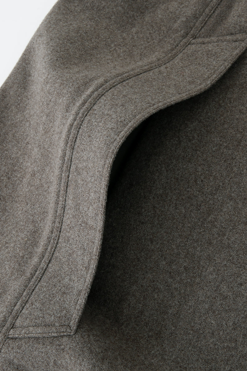 Brown long wool cape coat by JINSUN draped over a hanger, showcasing its textured fabric and elegant length.