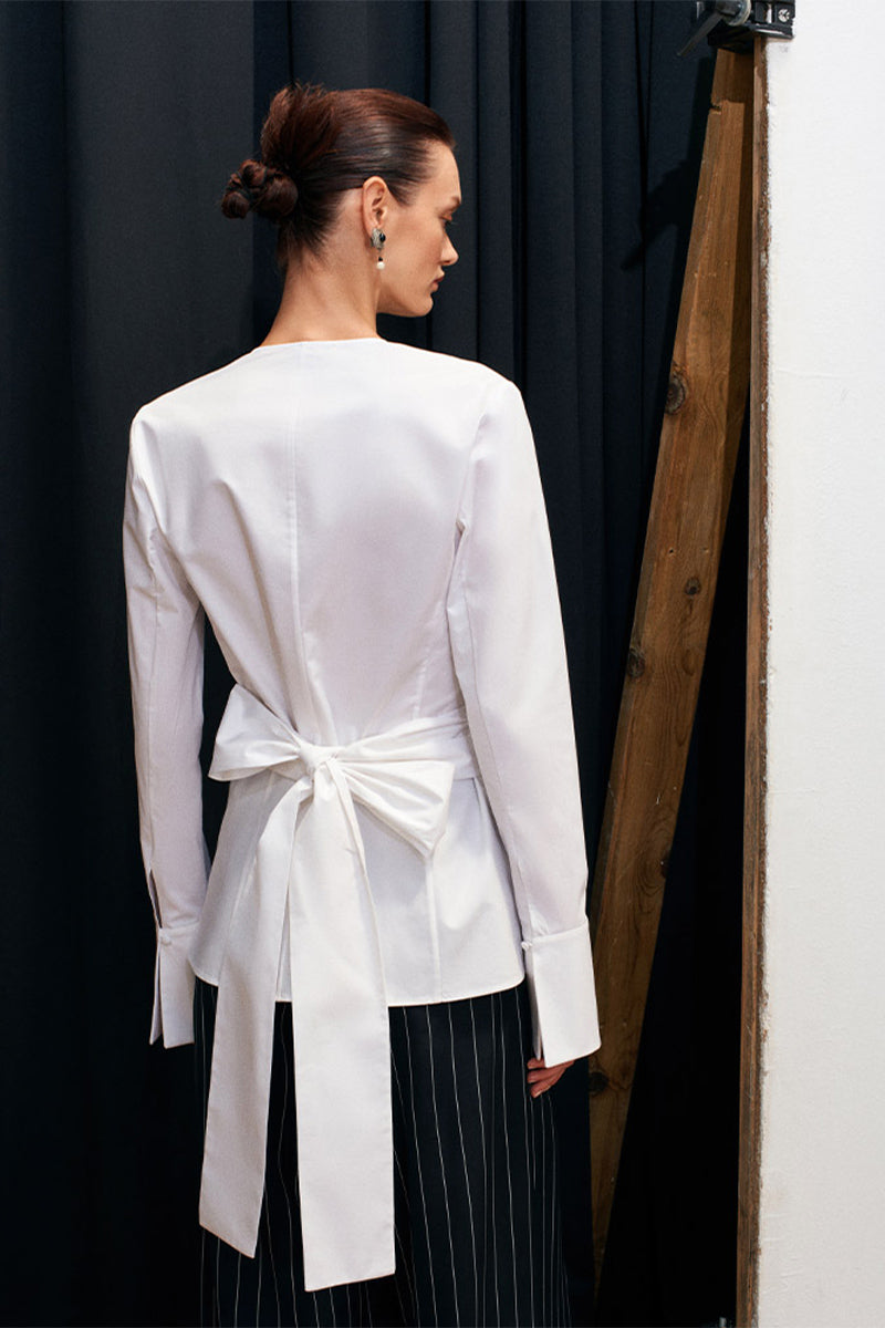 White Journey shirt by Acaria Studio displayed on a hanger with a classic collar and long sleeves.