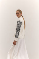 Fashionable DELEGAN jacket with decorative ornament details, displayed on a hanger with a neutral background.