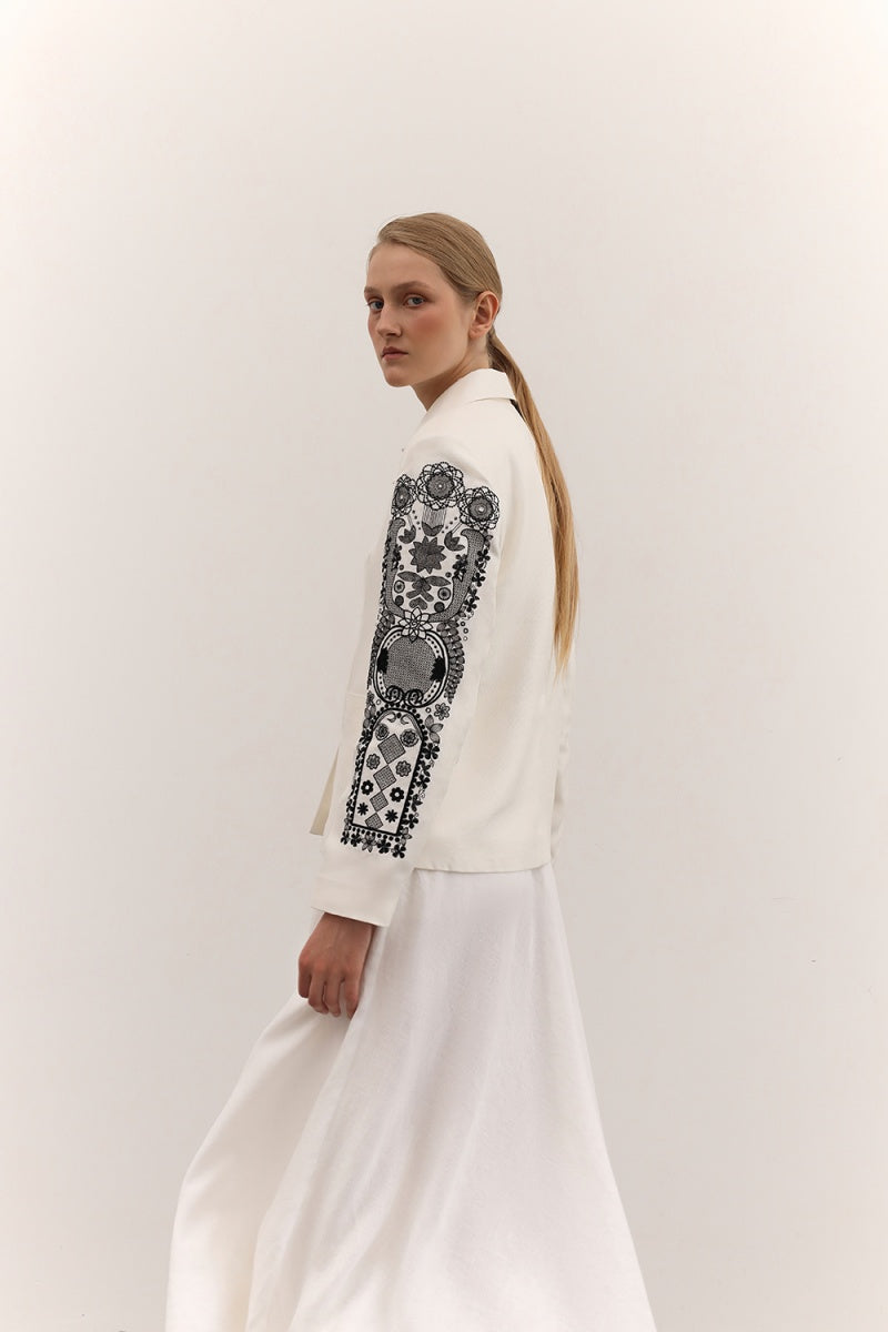 Fashionable DELEGAN jacket with decorative ornament details, displayed on a hanger with a neutral background.