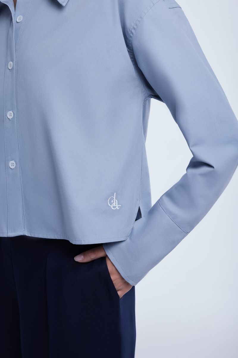 Dāl the Label cropped cotton button-down shirt with long sleeves and a classic collar, in a light, breathable fabric.