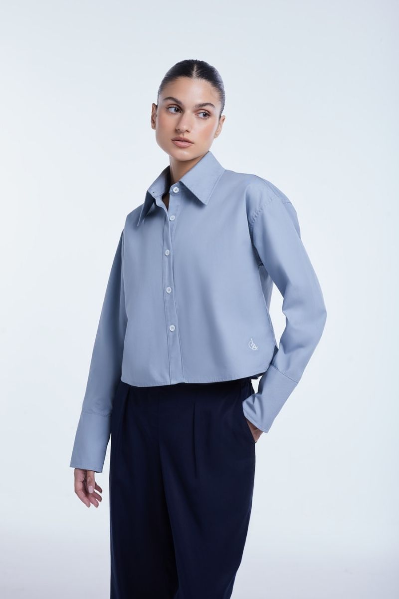 Dāl the Label cropped cotton button-down shirt in white with long sleeves and a classic collar, styled on a mannequin.