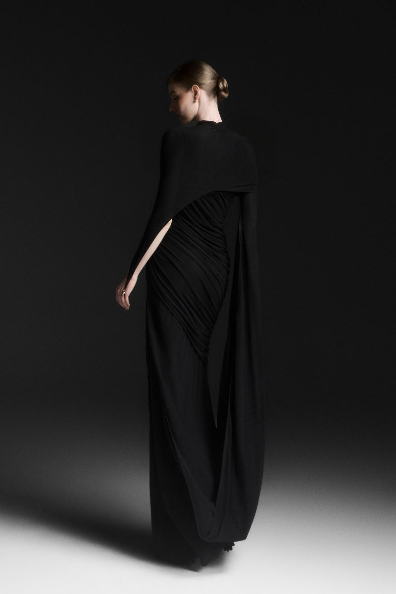 Black Maison Des Copains Celiora cape sleeve floor-length maxi dress displayed on a model, elegant and flowing design.