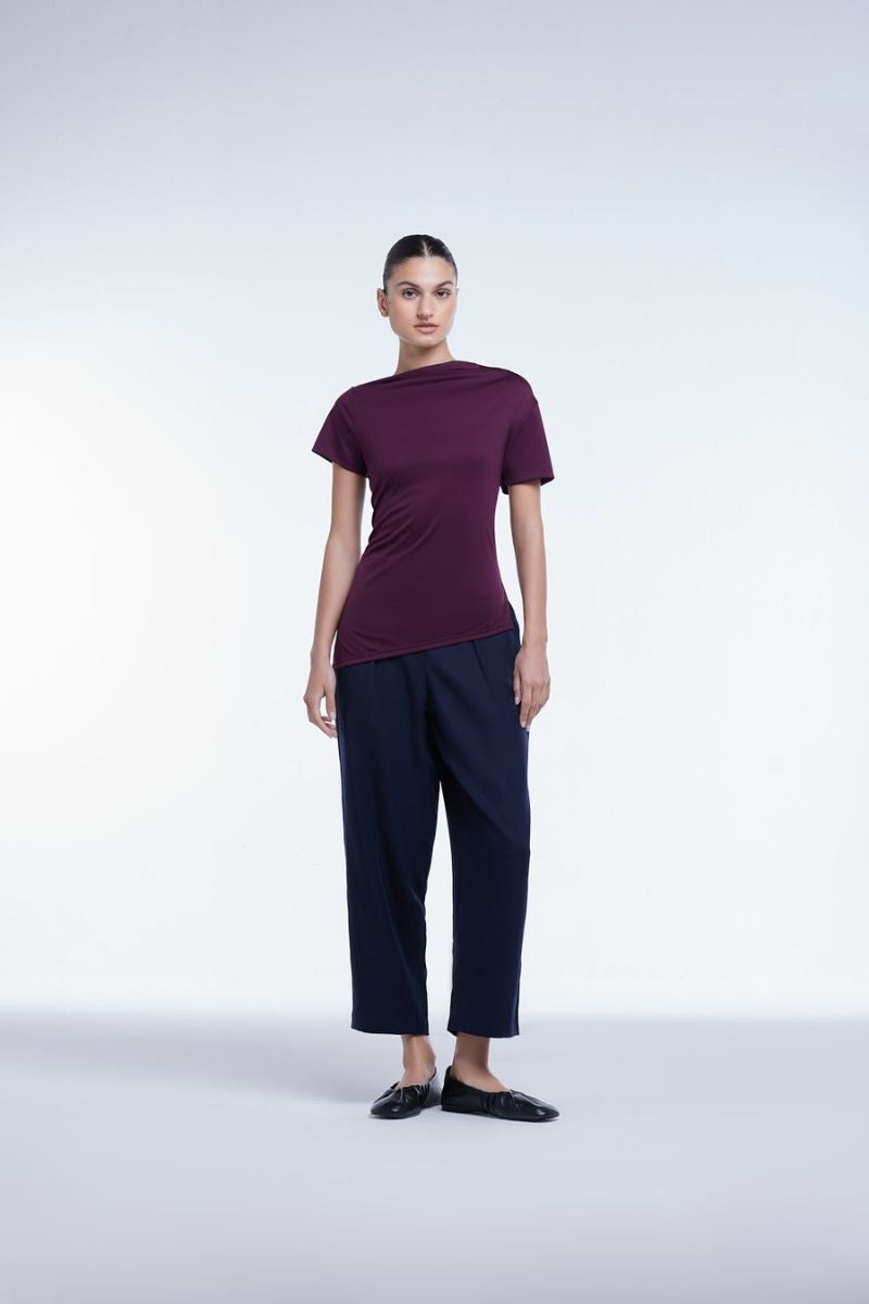 Dāl the Label asymmetrical short sleeve top in soft fabric, featuring unique hemline and modern design, worn by a model against a neutral background.