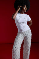 Onalaja Tene beaded white pants with intricate bead detailing and a relaxed fit, shown on a model in a stylish outdoor setting.