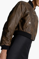 Acaria Studio Nostalgie leather bomber jacket with classic design, brown leather, and ribbed cuffs, displayed on a hanger.