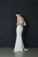 Elegant ivory gown by JINSUN with botanical embellishments, featuring flowing fabric and intricate floral details.