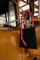 Black shoulder bag by SAC DE SOUL with a serpent design, featuring red and white accents on the textured surface.