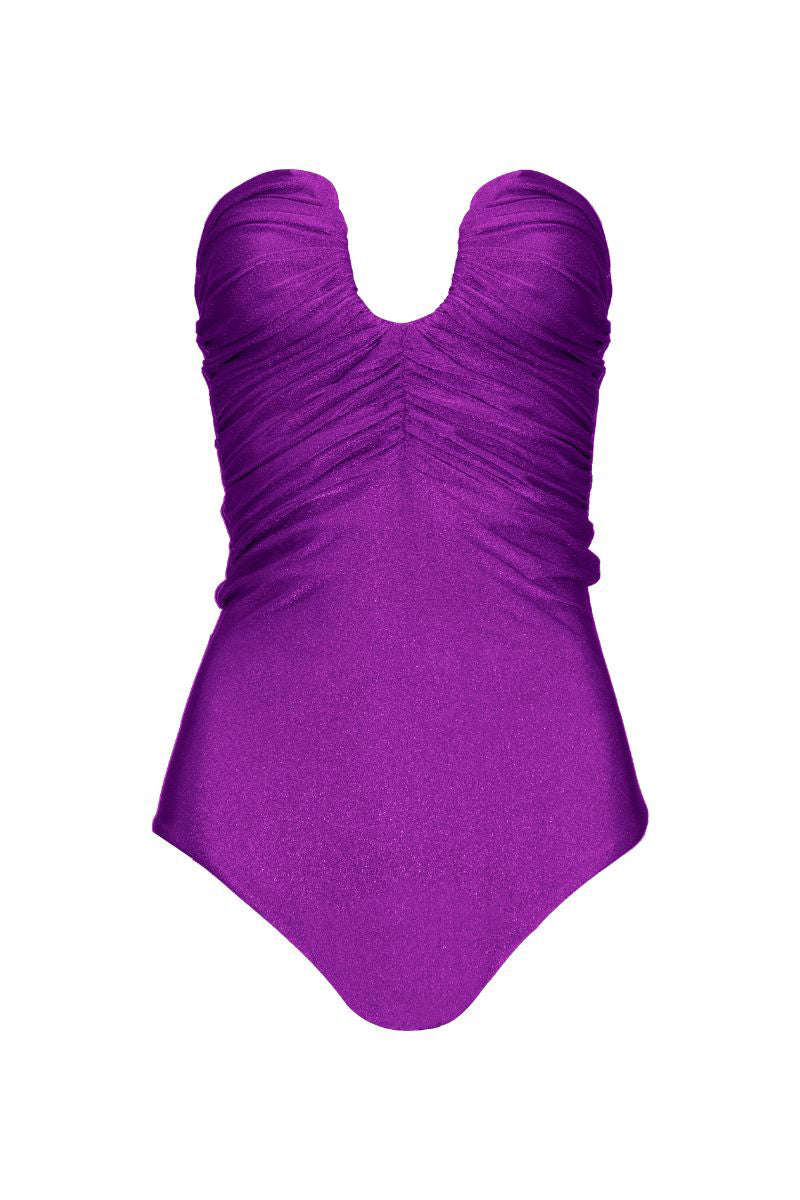 Laura Escobar SERRANIA purple one-piece swimsuit with sleek design, shown on a model in a sunny outdoor setting.