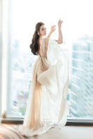 Elegant nude silk evening gown by Do Long, flowing design with a fitted silhouette and subtle draping, perfect for formal occasions.