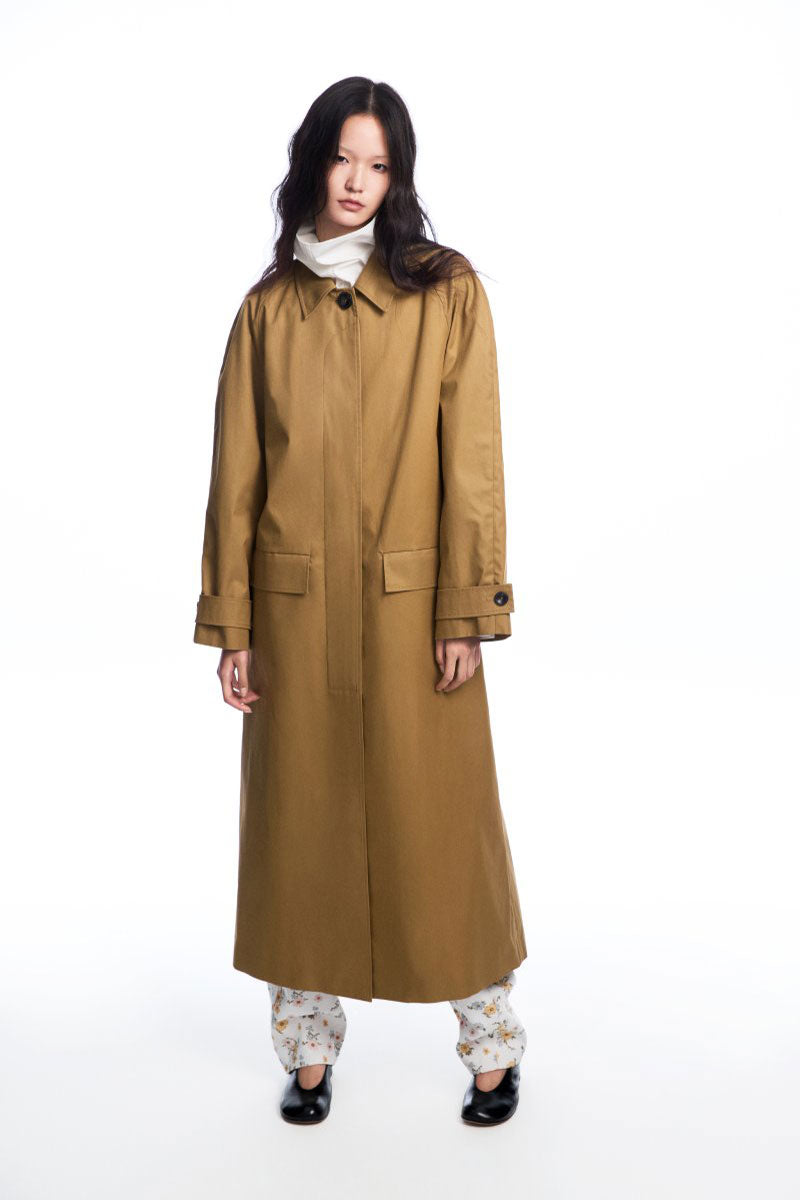 Long brown collared trench coat by Chictopia, shown hanging on a rack with a classic double-breasted design and belted waist.