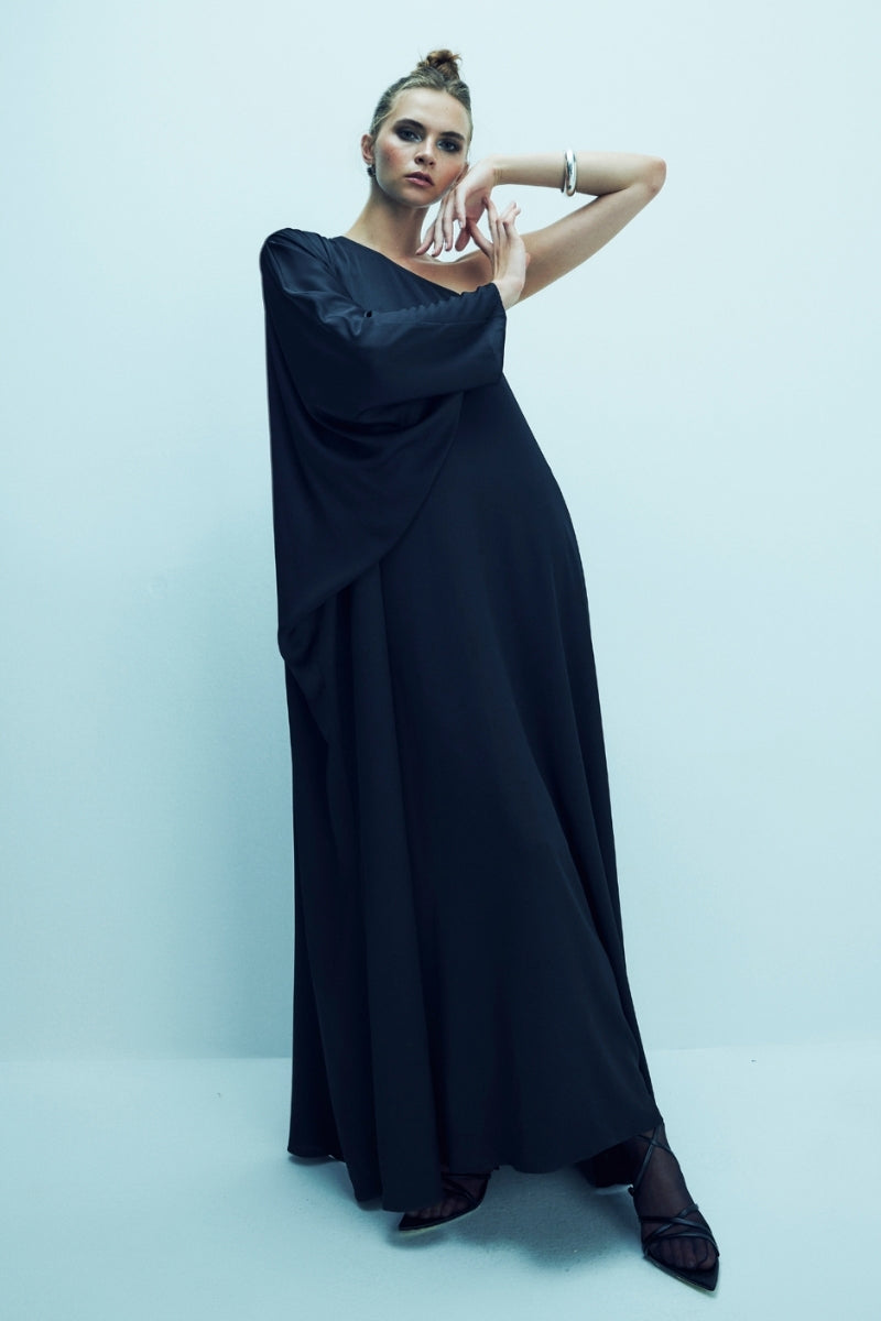 Black satin maxi dress with one-shoulder design by Nazlı Ceren, featuring elegant draping and a flowing silhouette.