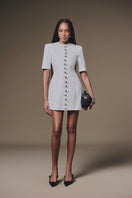 White buttoned mini dress by Keira Tong, featuring a fitted silhouette and short sleeves, displayed on a mannequin.