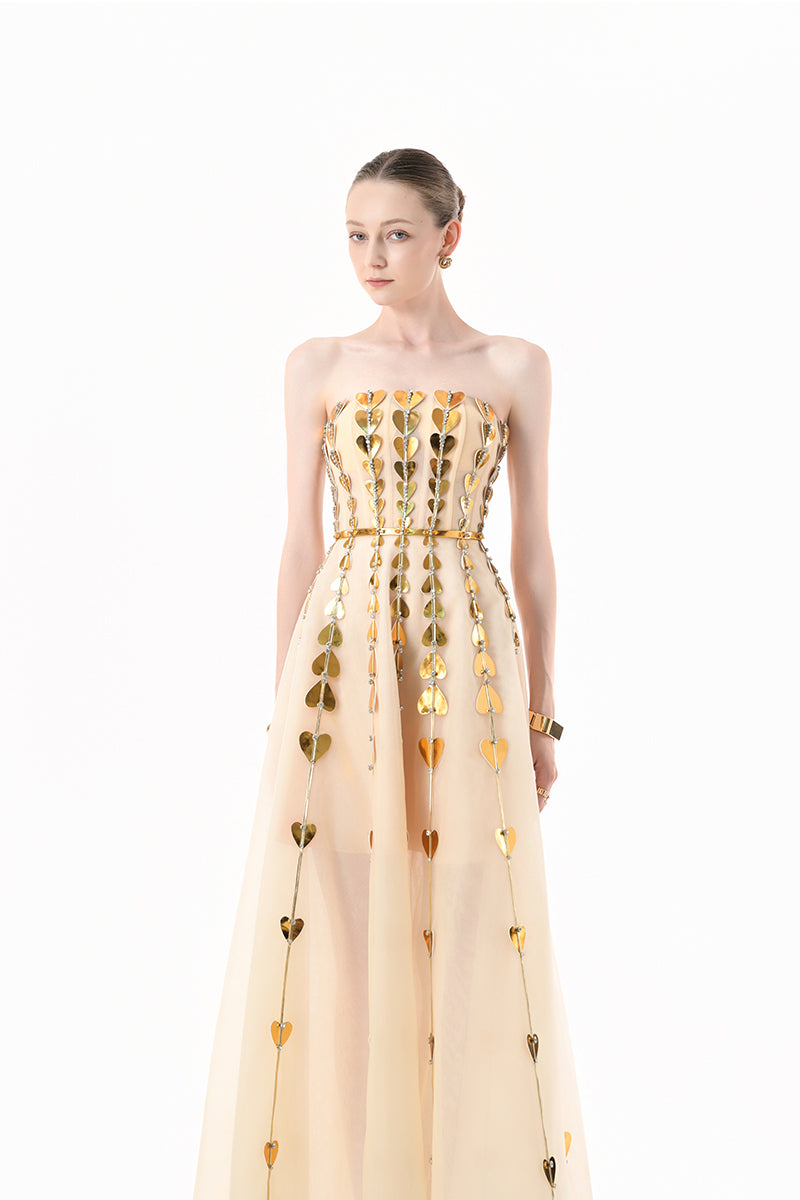 Elegant champagne metallic gown with heart embellishments from Happy Clothing, featuring a flowing design and intricate detailing.