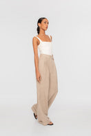 Dāl the Label linen wide-leg pants in neutral fabric, featuring a relaxed fit and high waist, displayed on a hanger.