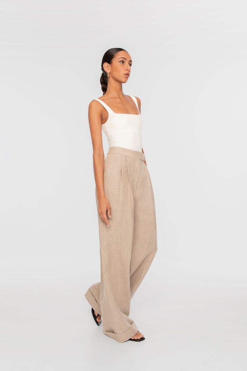 Dāl the Label linen wide-leg pants in neutral fabric, featuring a relaxed fit and high waist, displayed on a hanger.