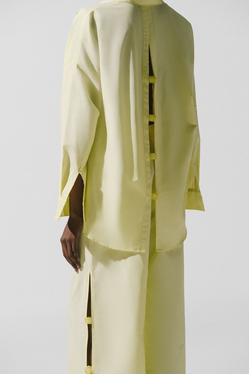 Baobab Wayra shirt in Limone color, lightweight cotton shirt with a relaxed fit and button-up front, displayed on a hanger.