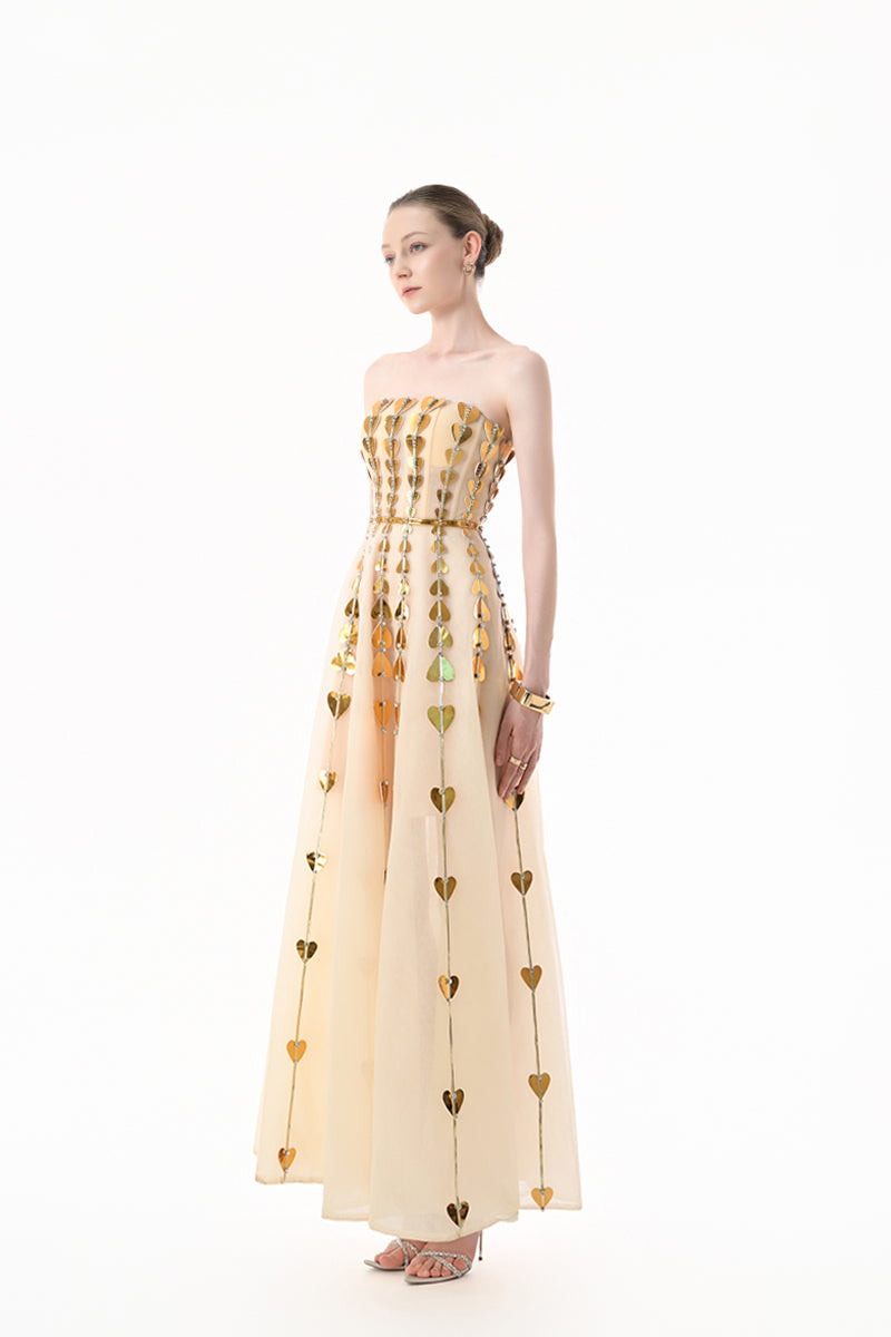 Elegant champagne metallic gown with heart embellishments by Happy Clothing, featuring a flowing design and intricate detailing.