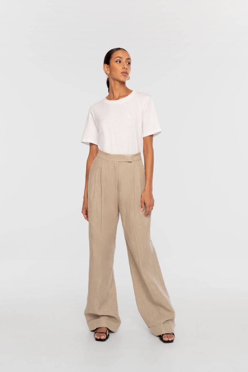 Light beige Dāl the Label linen wide-leg pants shown on a model, featuring a relaxed fit and flowing fabric.