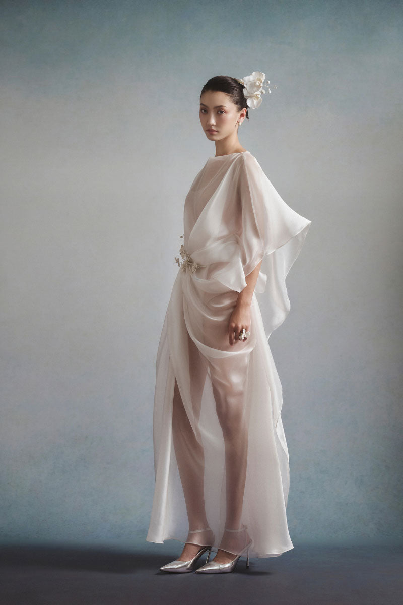 White Plan Aurelia draped maxi dress displayed on a model, featuring flowing fabric and elegant design.