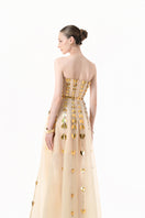 Elegant champagne metallic gown by Happy Clothing featuring heart-shaped embellishments and a flowing, glamorous design.