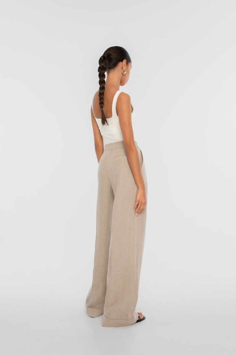 Dāl the Label linen wide-leg pants in neutral fabric, featuring a relaxed fit and high waist, shown on a model.