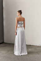 Silver satin maxi skirt by Nazlı Ceren with a flowing design and elegant sheen, showcased on a neutral background.