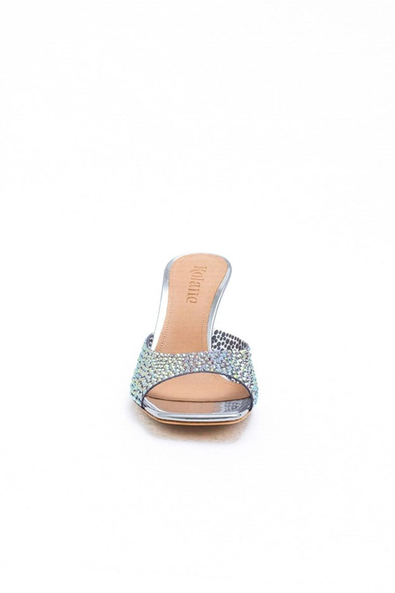 Kolane Greta mule sandals in silver crystal transparent with open toe and chunky heel, showcasing a stylish, modern design.