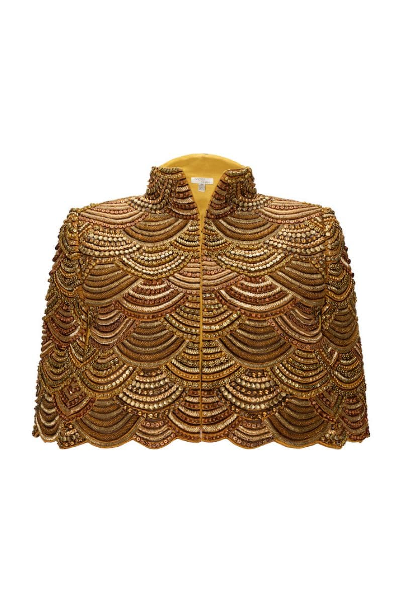 Nadya Shah Gilt De Havilland Cape jacket with luxurious gold-toned fabric and elegant draped design, displayed on a neutral background.