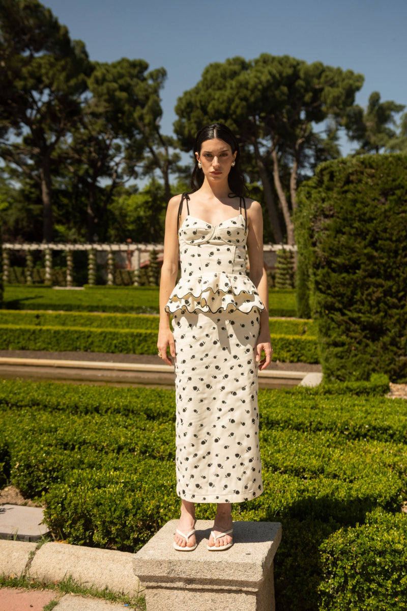 Estefania Rosita peplum top in ivory and black, featuring a fitted bodice and flared peplum hem, styled with long sleeves.