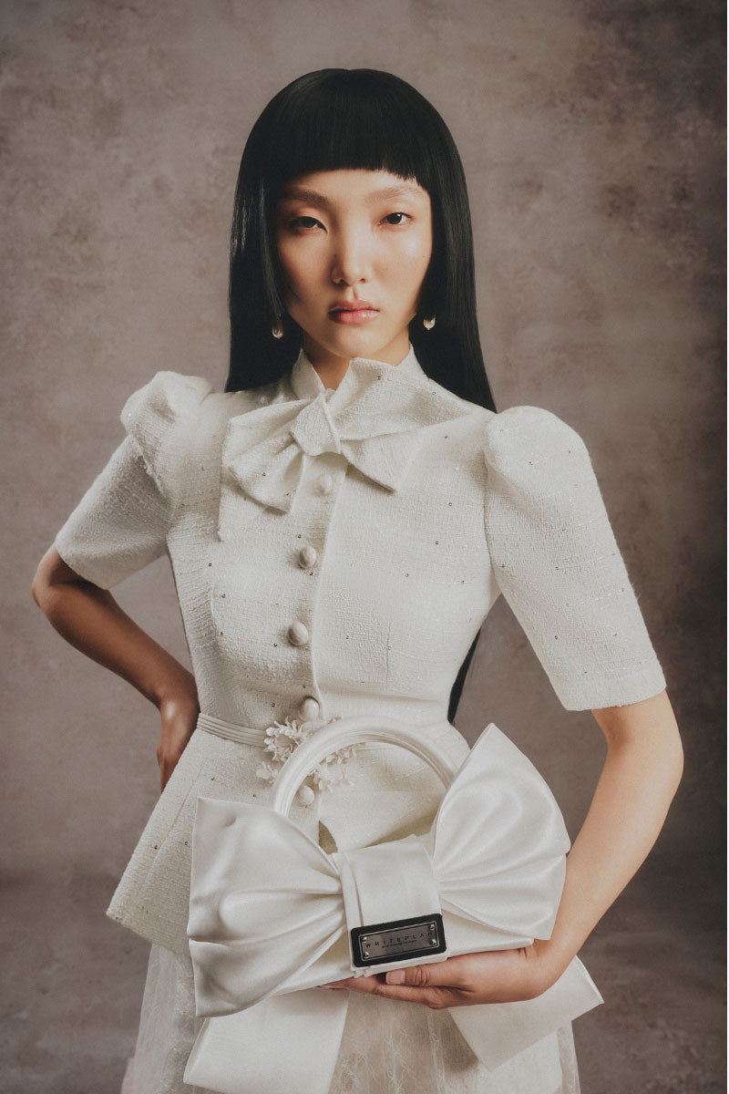 Ivory bow top handle bag by White Plan featuring a sleek design and elegant bow detail, perfect for stylish occasions.