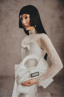 Ivory bow top handle bag by White Plan, stylish and elegant accessory with a bow detail and structured design.