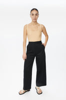 Dāl the Label cotton twill pants featuring a relaxed fit, natural beige color, and front pockets, shown on a model.