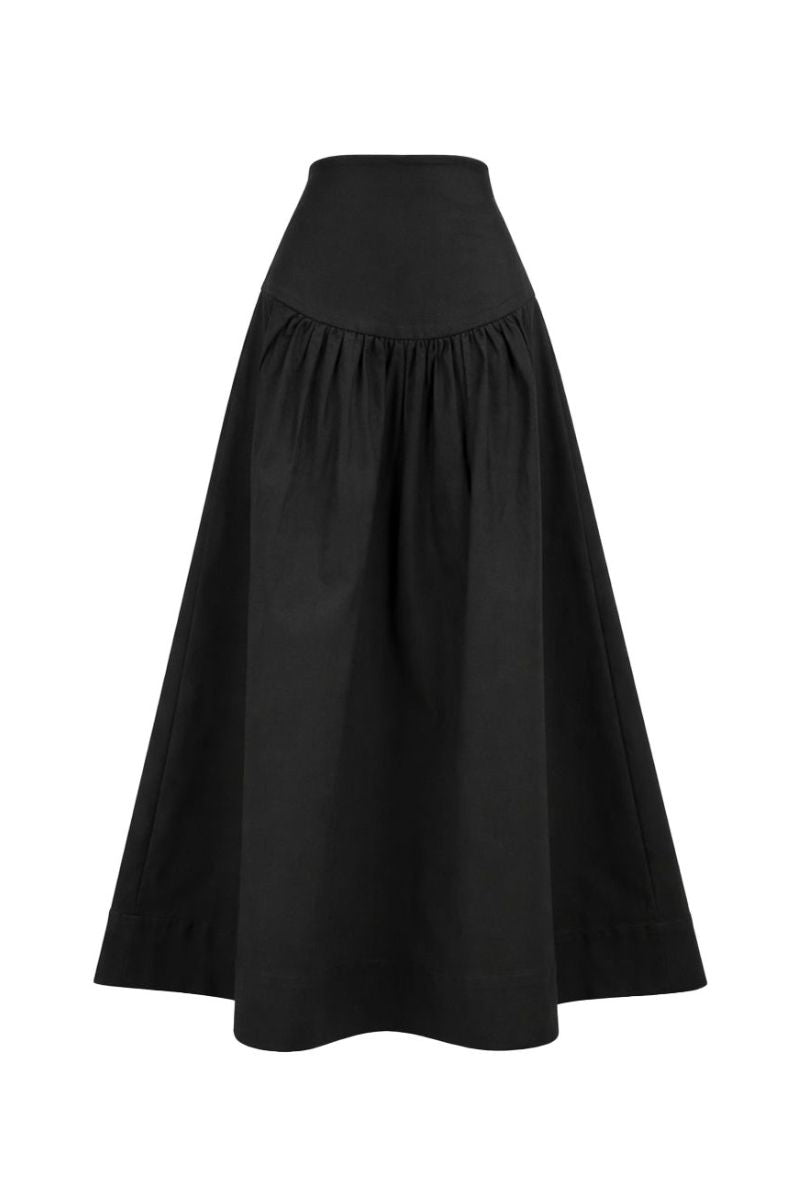 Black Ginevra maxi skirt by ANA + MARIA, flowing fabric and high waist design, shown on a model in a casual setting.