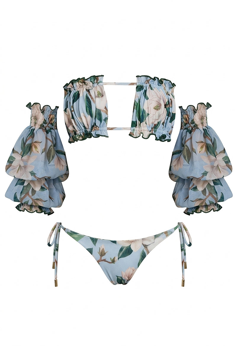 Nur Karaata Misty Mirage bikini set in vibrant floral print, featuring triangle top and matching bottoms on a sandy beach backdrop.