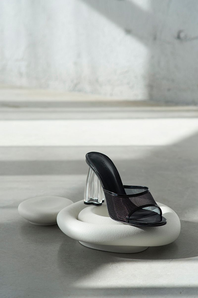 Black patent Fiorellini glass mules sandals by House of Atana featuring sleek design and transparent glass heel detailing.