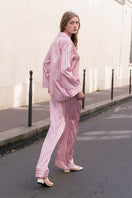 Pink striped silk pajama set from Not Just Pajama's Museum of Crush collection, featuring a long sleeve top and matching pants.