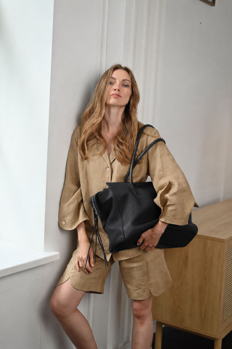 Black VIKELE STUDIO tote bag with shoulder straps, made of durable fabric, shown from a side view with open top and spacious interior.