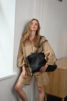 Black VIKELE STUDIO tote bag with shoulder straps, made of durable fabric, shown from a side view with open top and spacious interior.