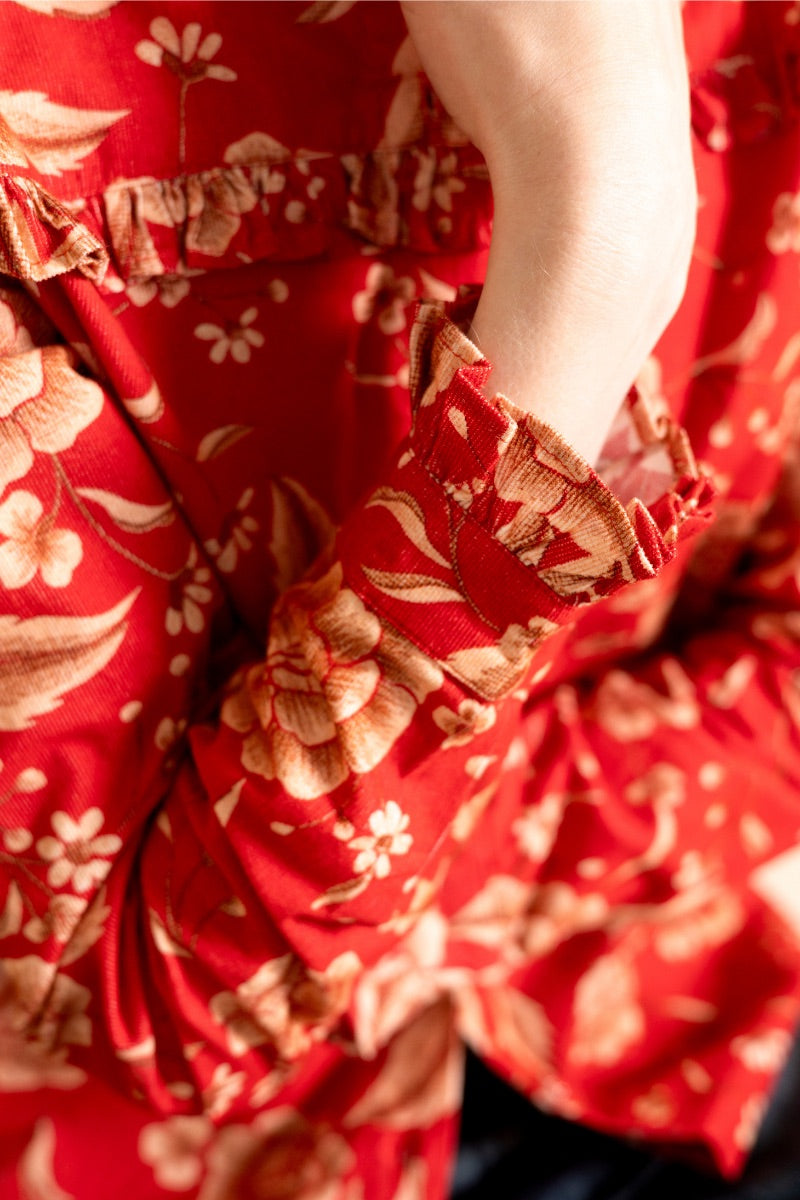Raishma Esme red shirt displayed on a hanger, showcasing its vibrant color and stylish design.
