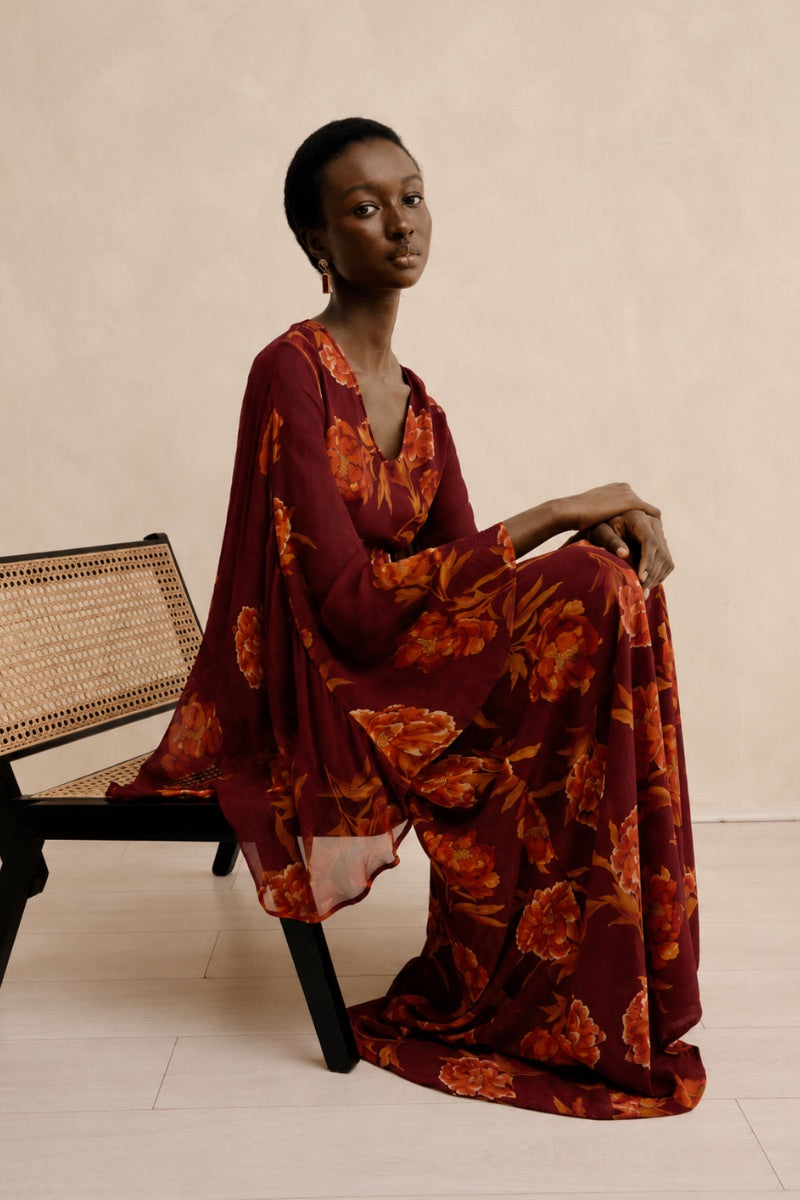 Red Raishma Karina maxi dress shown on a model, featuring a flowing silhouette and elegant design for formal occasions.